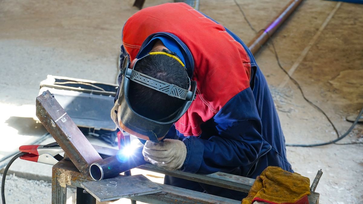 The professional welder works with argon-arc welding. Welds a pipe with a pipe DN50. Butt weld.